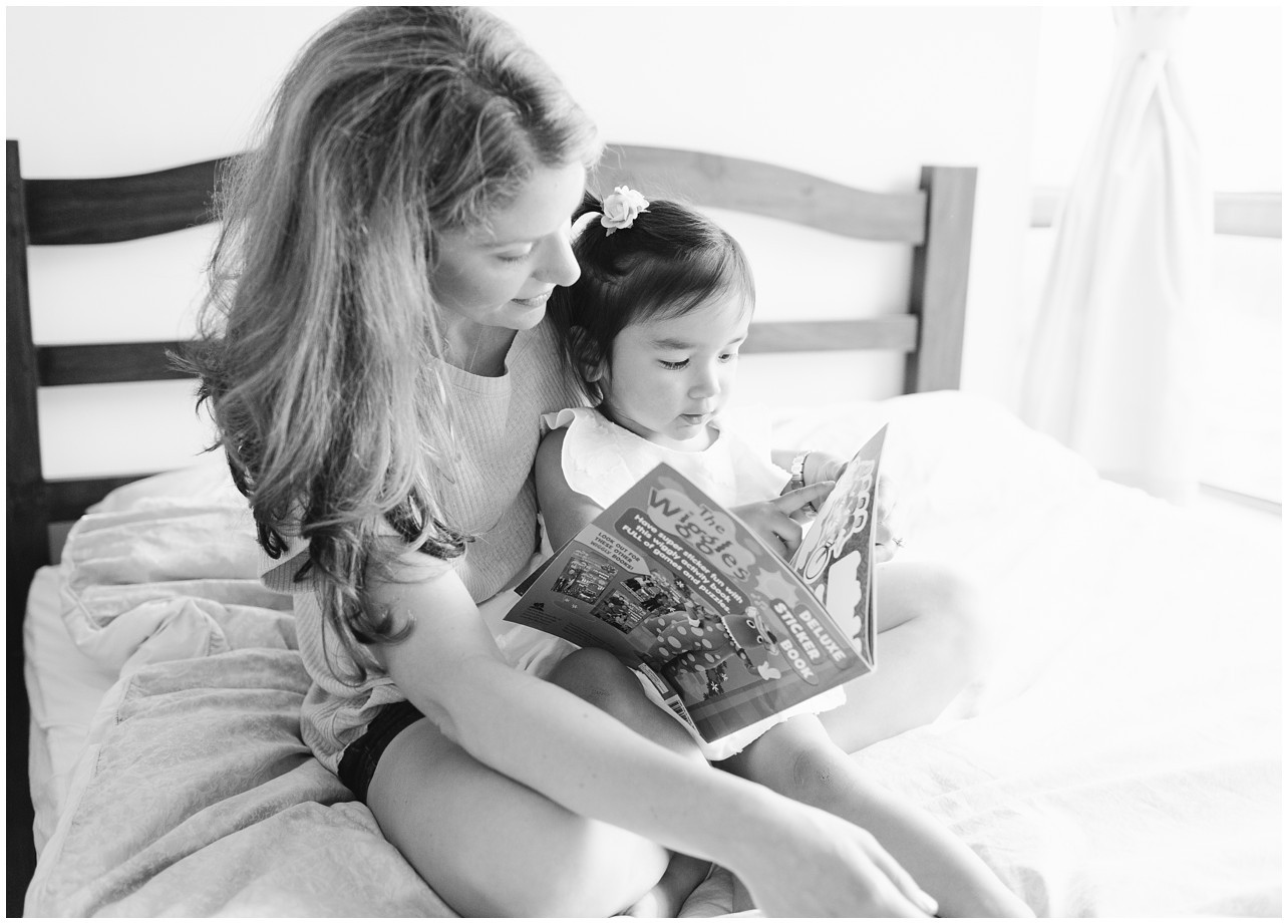 Mommy and me - black and white image - mom and a girl sitting on the bed and reading a book