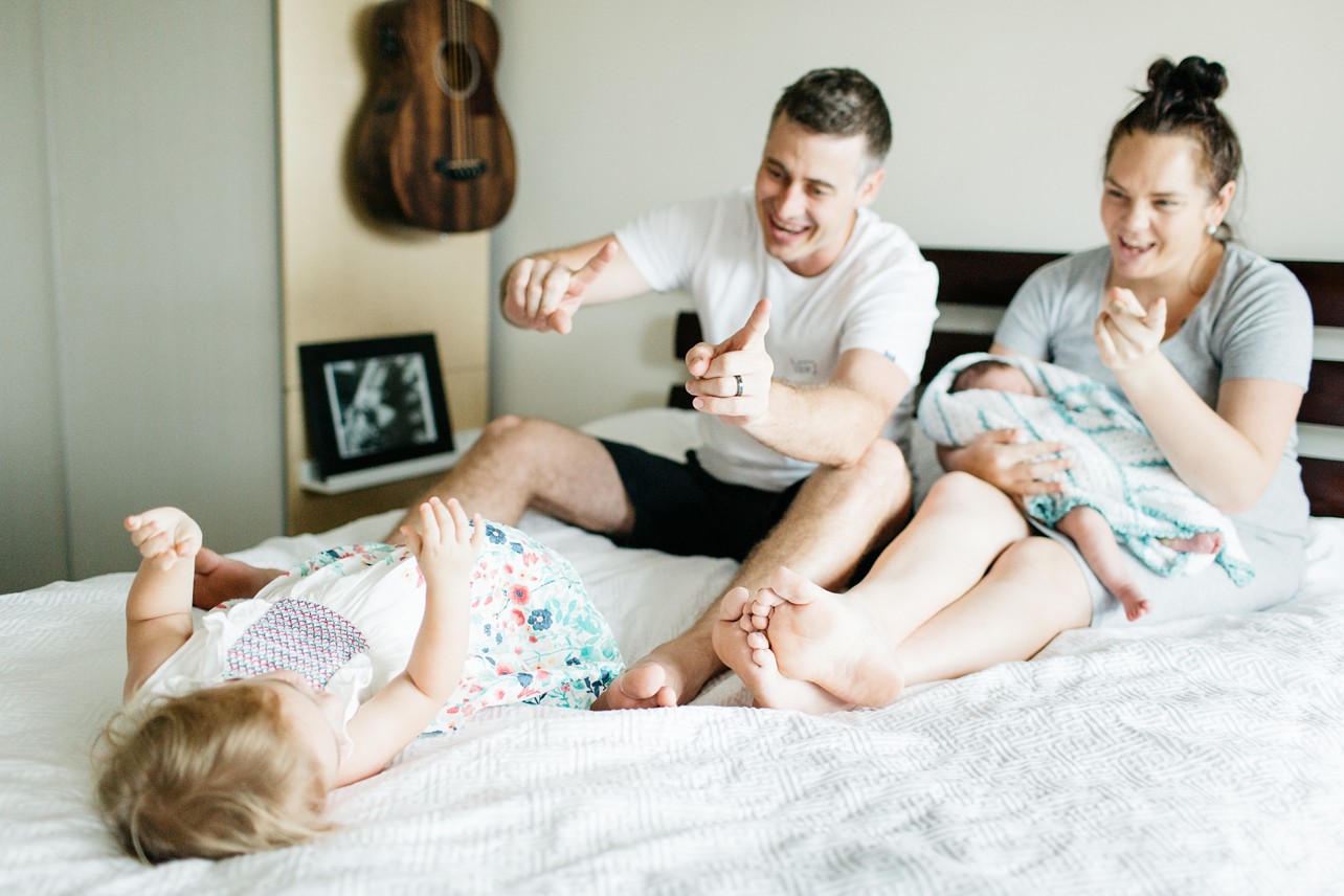 Newborn lifestyle session - family playing and singing on the bed