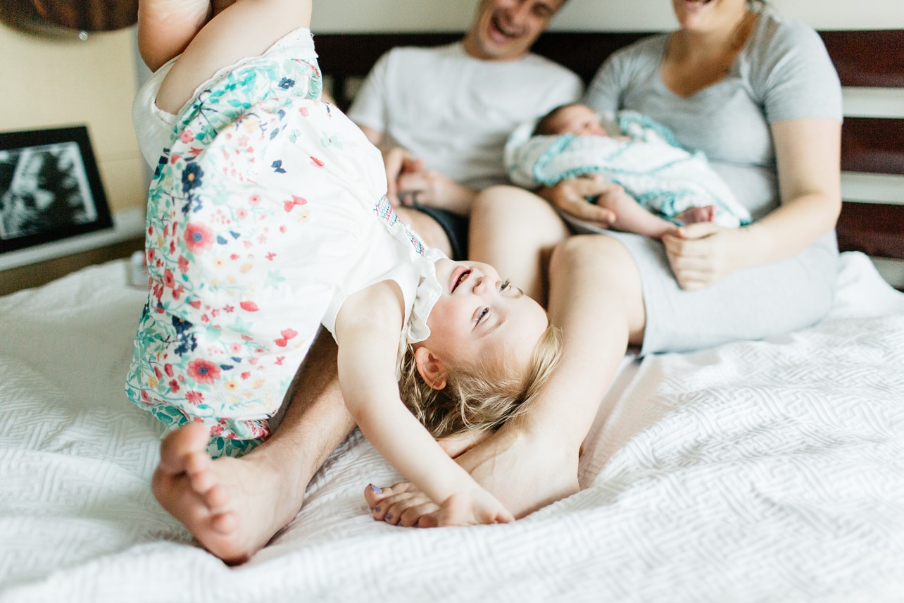 Newborn lifestyle session - family is playing on the bed
