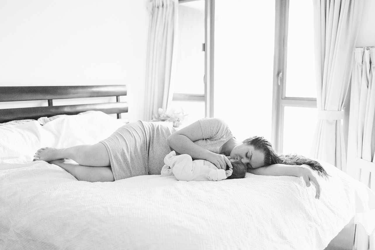 Newborn lifestyle session - newborn and his mama sleeping on the bed black and white
