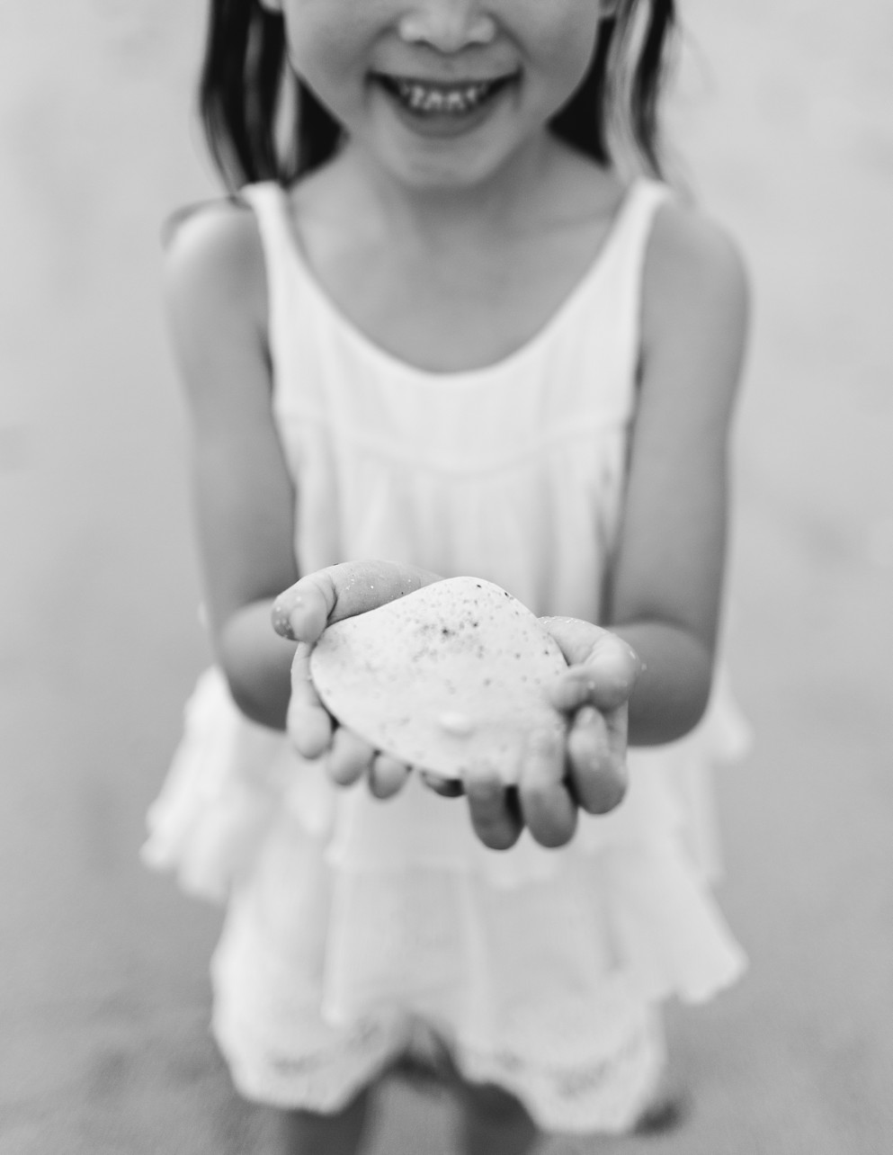 North Beach Discovery Bay - black and white - girl holding a big shell