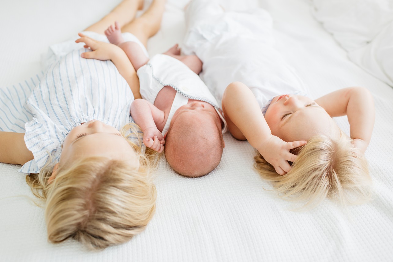 Newborn Home Lifestyle with Felix - sisters and a baby on the bed