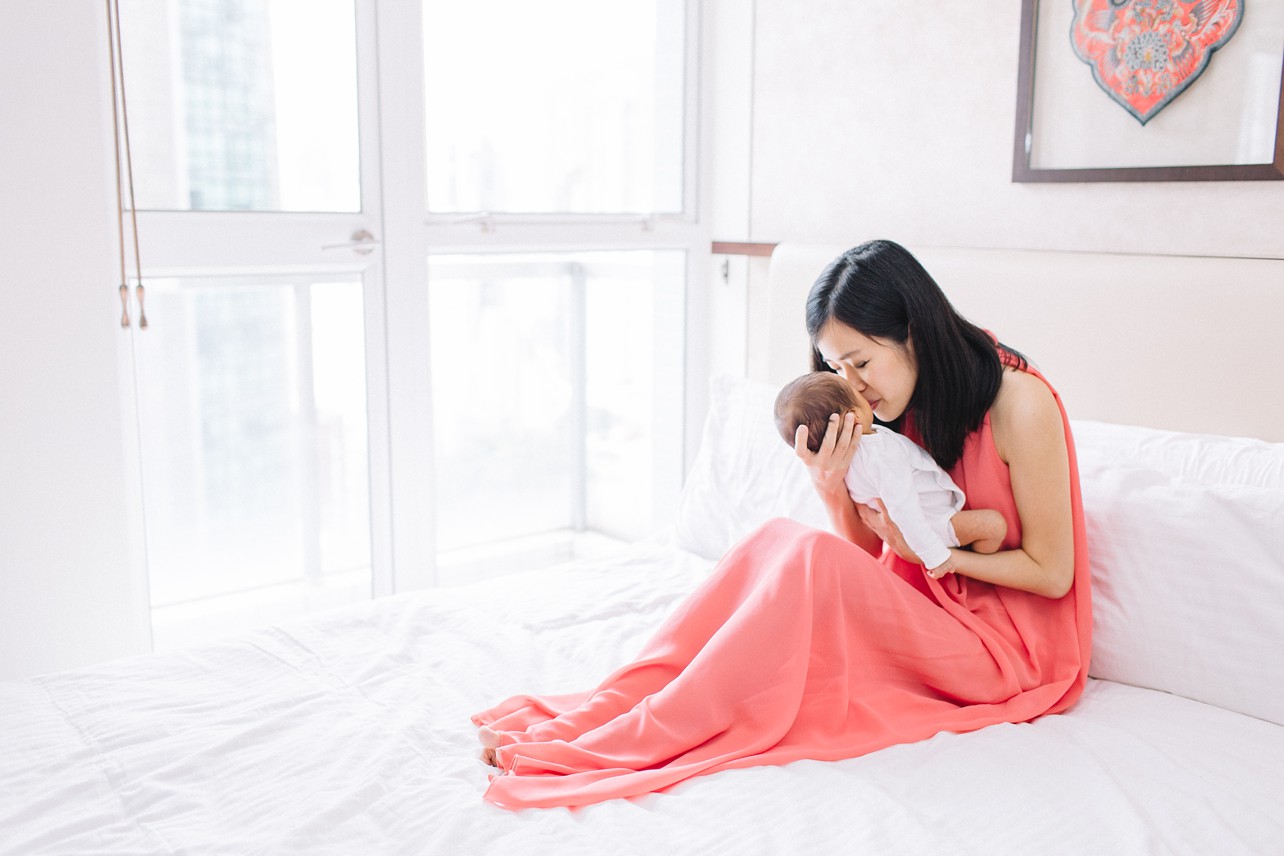 Newborn Session in Happy Valley with William - mom with coral dress with baby on the bed