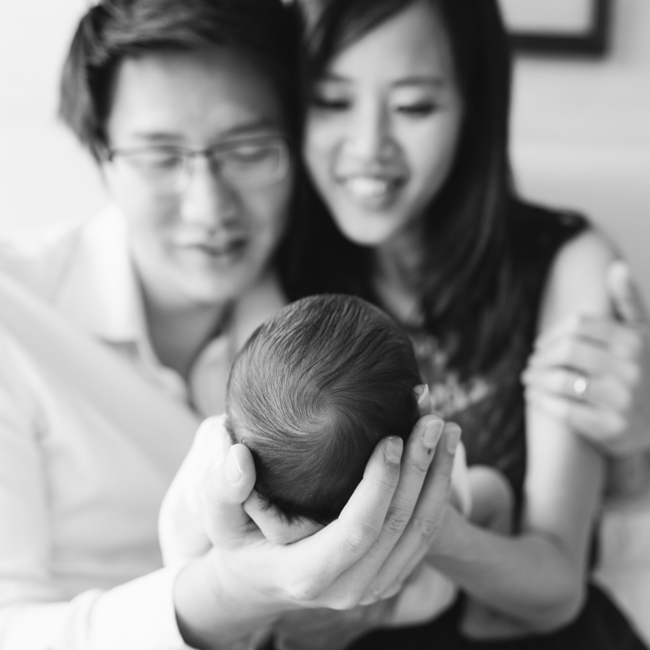 Newborn Session in Happy Valley with William - BW focus on baby's head and parents smiling in the background