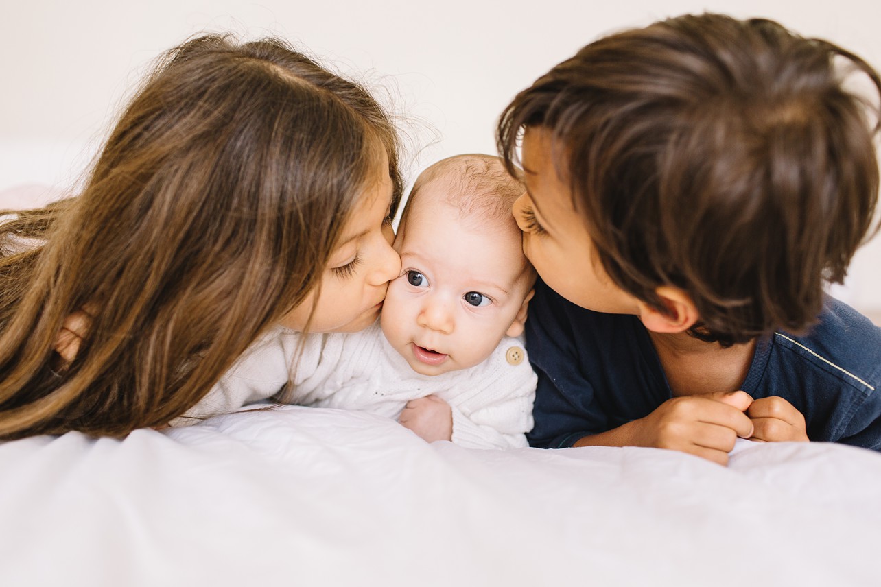 Cozy Family Session - big brother and sister are kissing their little brother