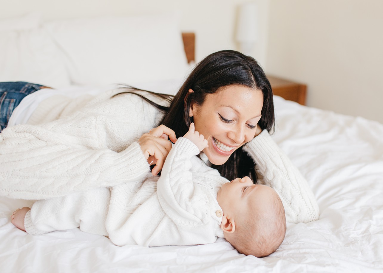Cozy Family Session - mommy is smiling at the little baby boy, both laying down