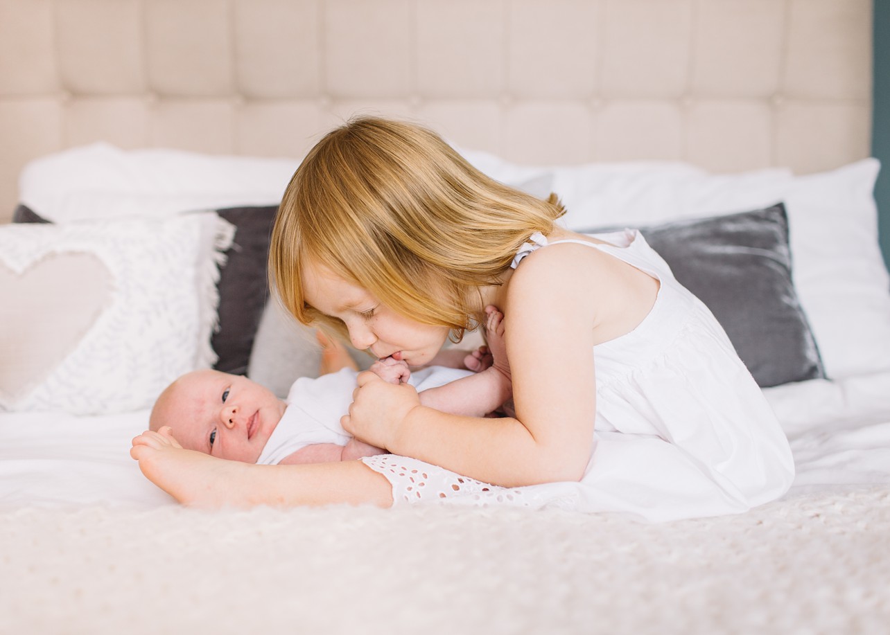 Newborn Photo - big sister is kissing baby's foot
