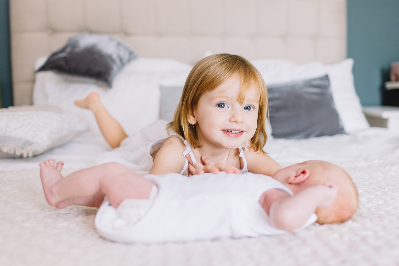 Newborn Photo - Proud big sister is laying with her little sister