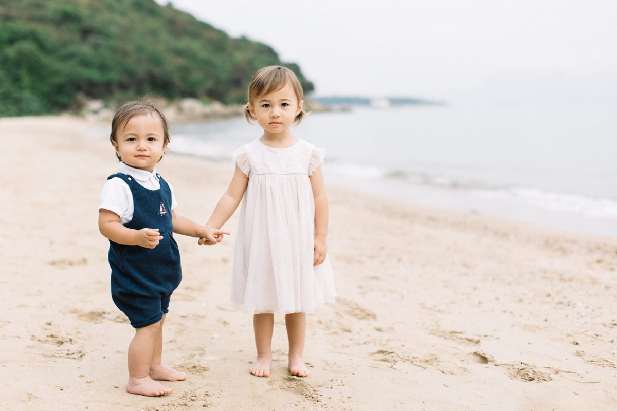 siblings holding hands on the beach