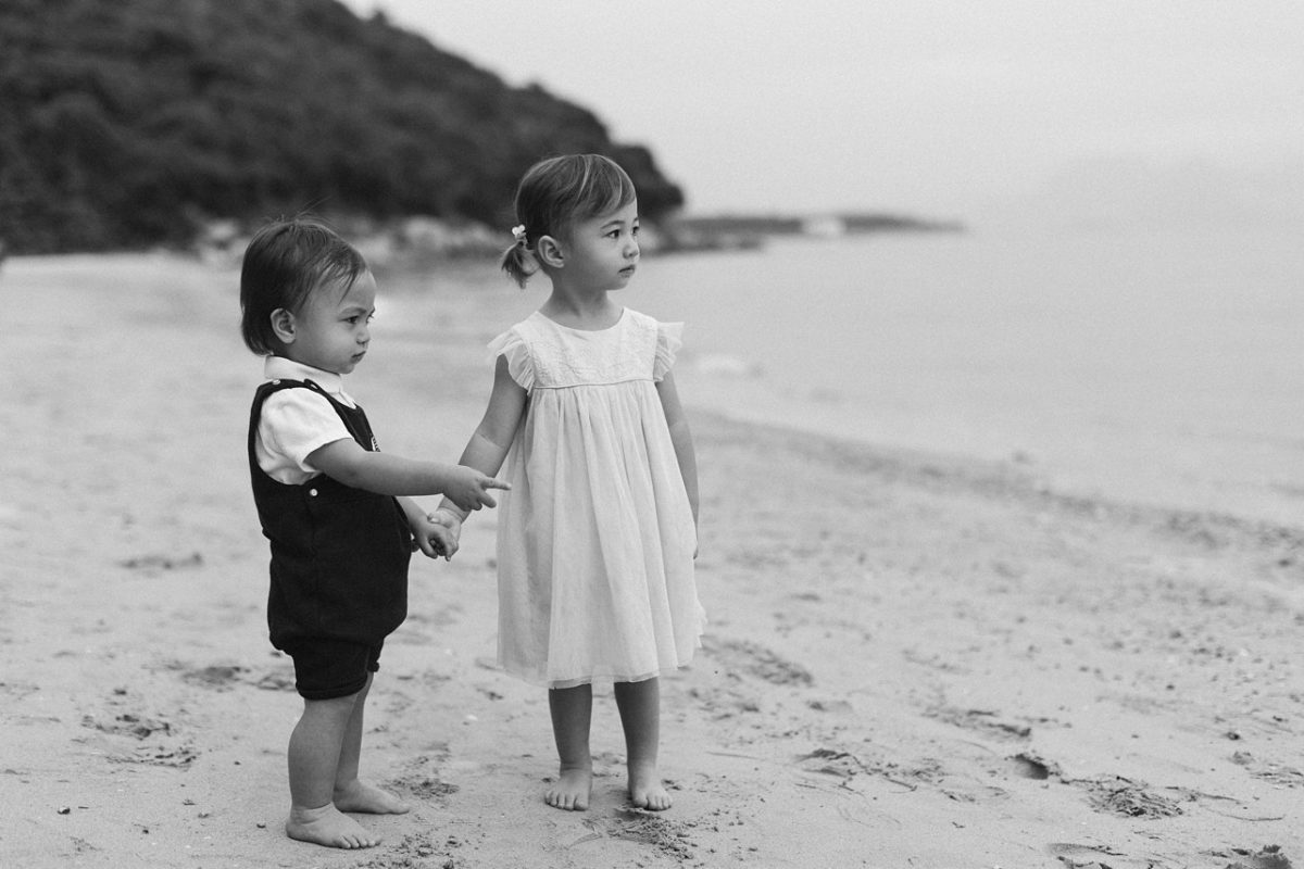 bw image of siblings on the beach holding hands