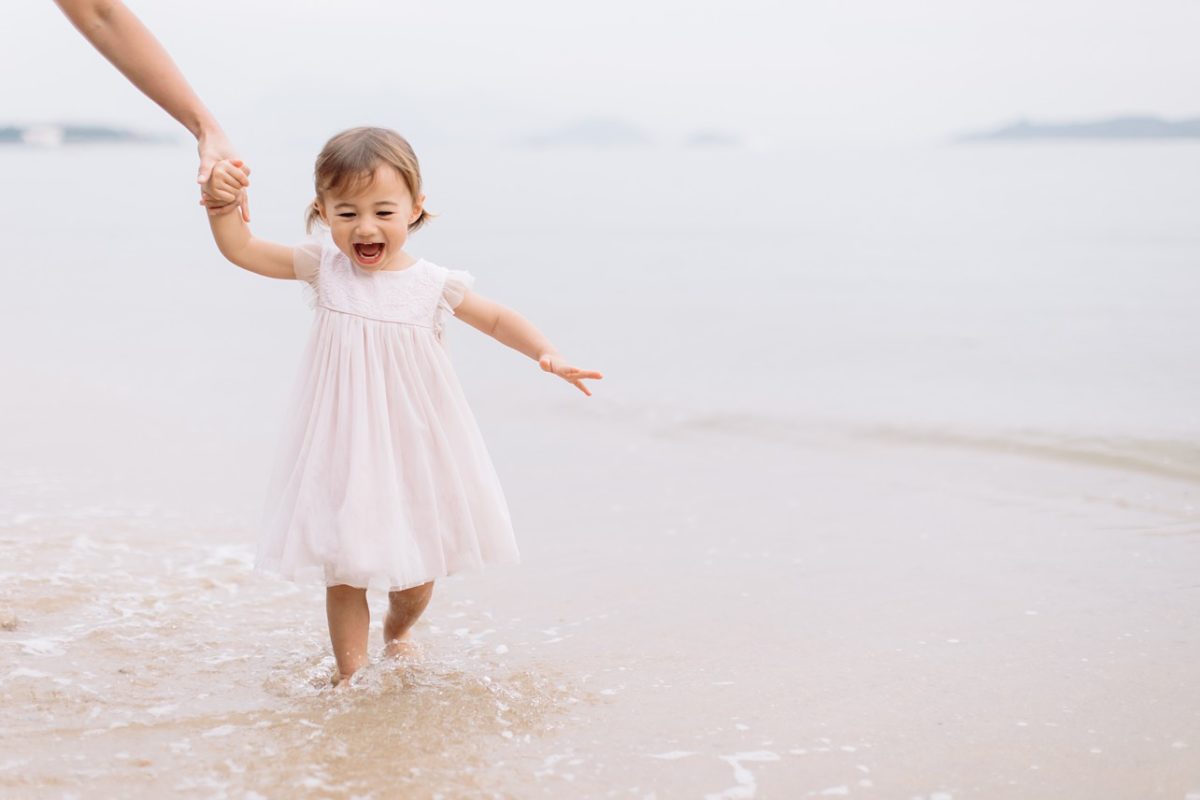 girl in pink dress is having so much joy on the beach
