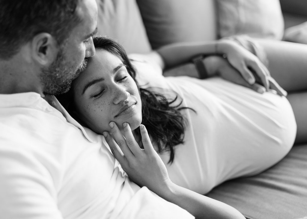 pregnant mom is peacefully relaxing on dad shoulder in black and white image