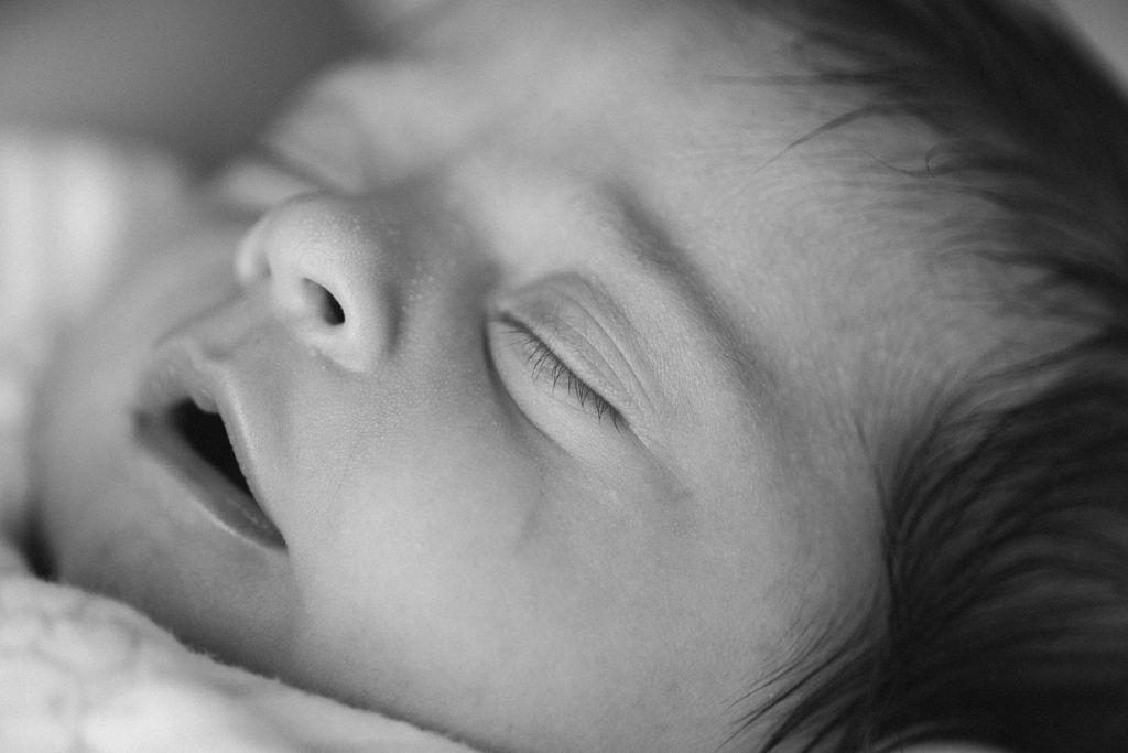 sleeping baby's side face close up in black and white, baby's mouth is open