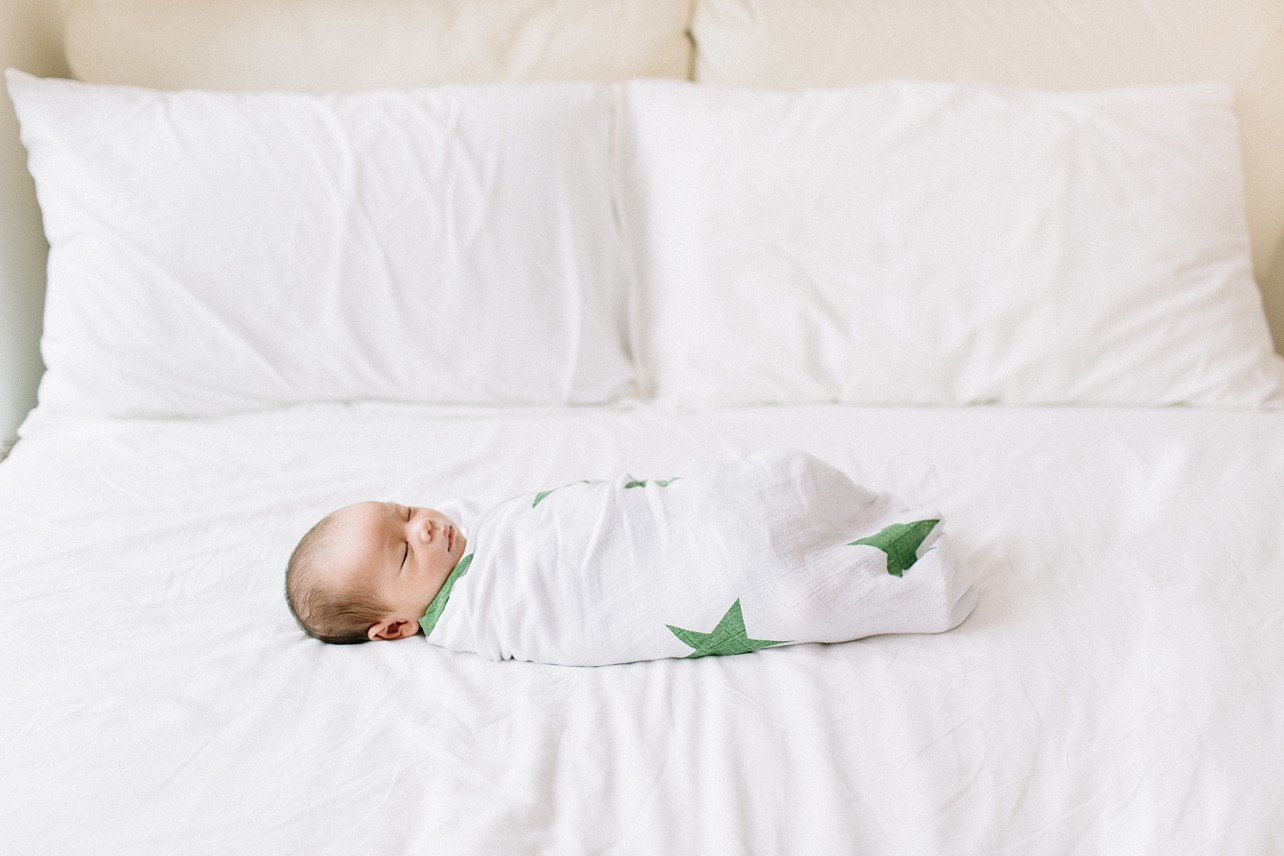 baby who is wrapped in a green stars print