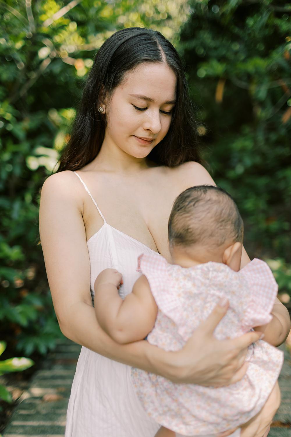 mother is holding her baby who is in a pink dress