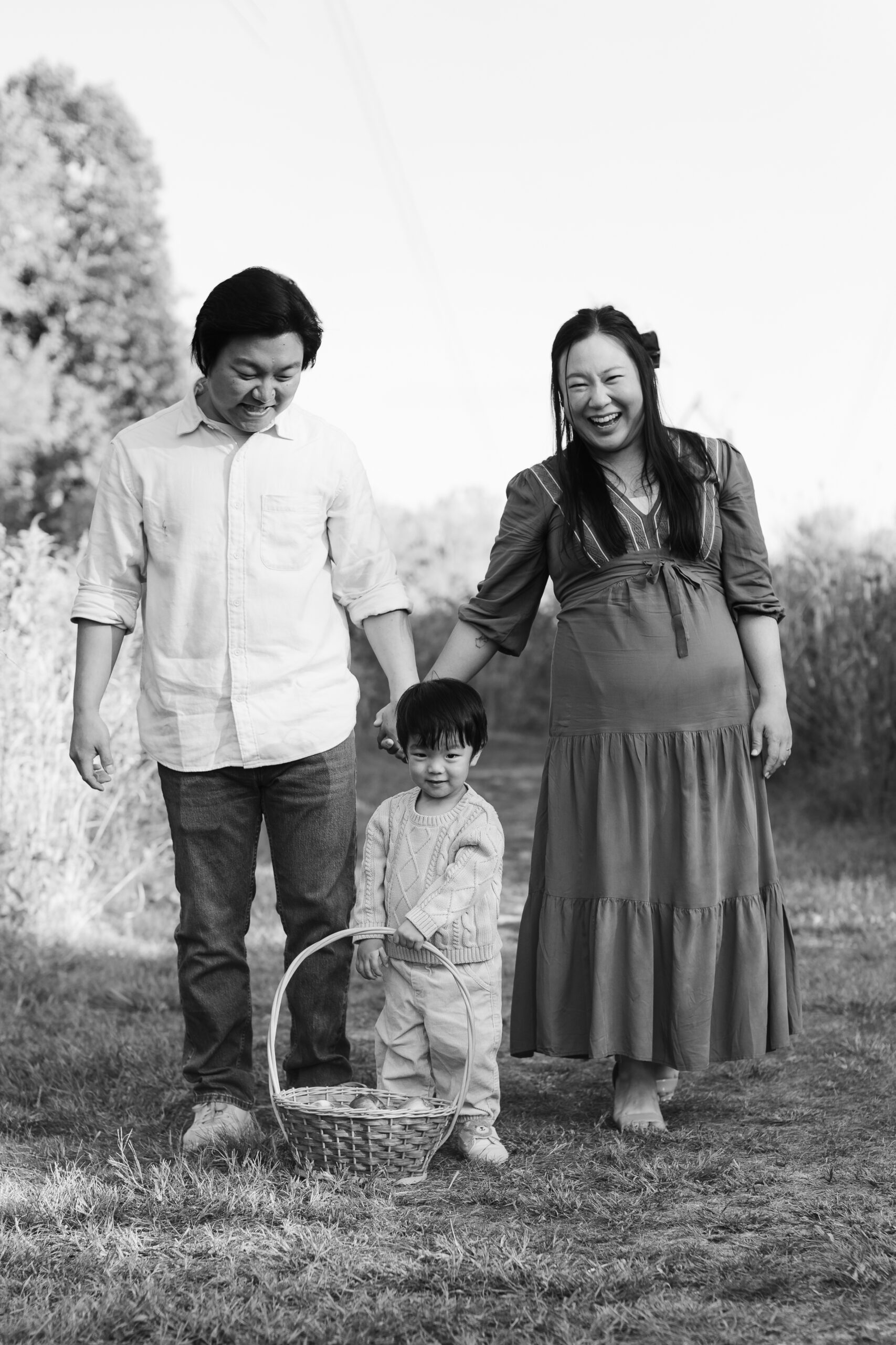 Mom, dad, and toddler son holding fruit basket. 