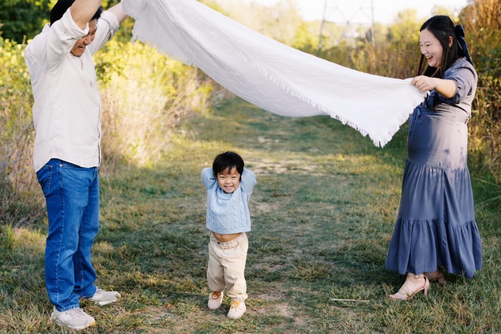 Father and mother hold blank tunnel while son plays underneath. 
